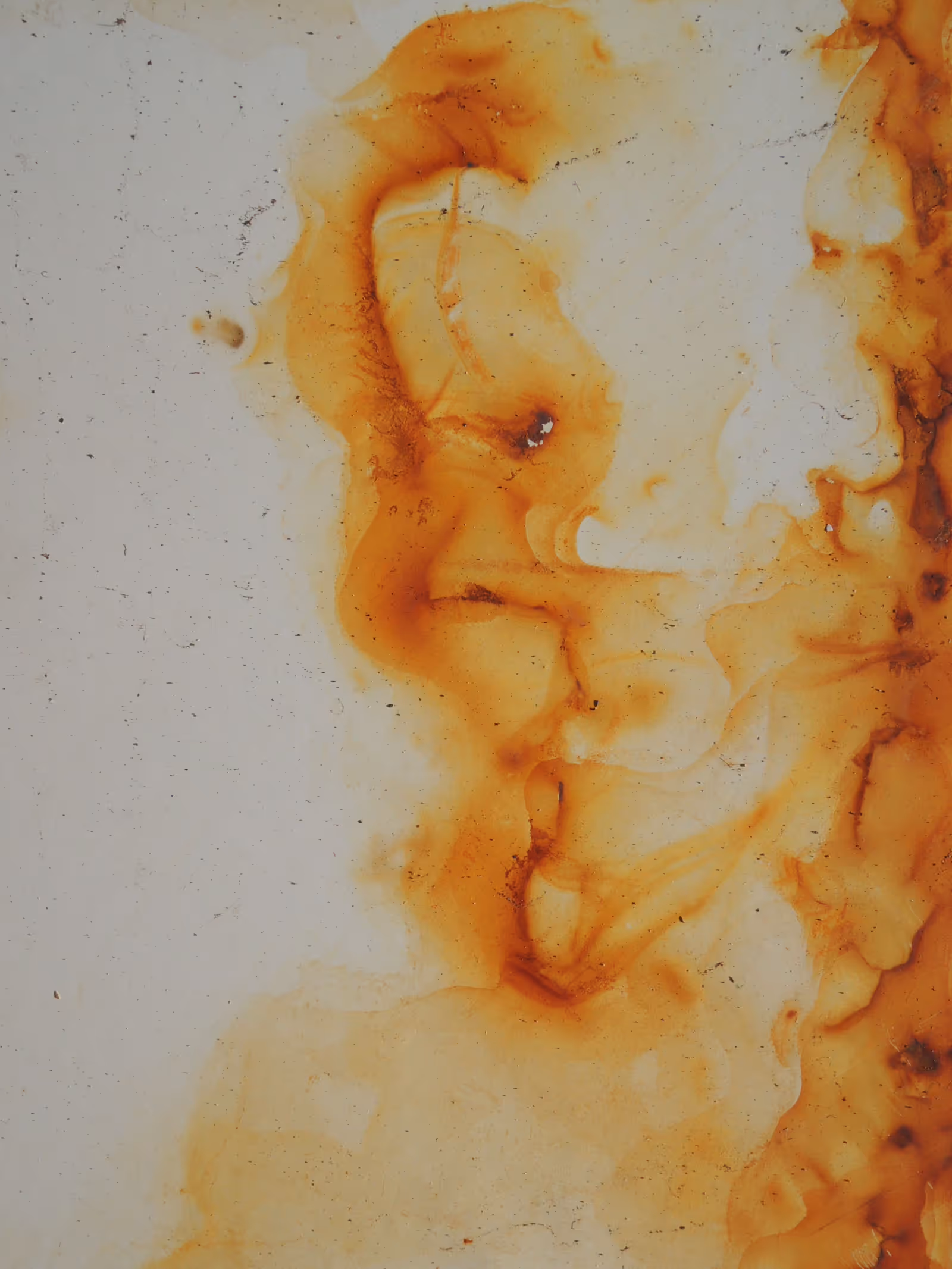 Rust-orange iron staining bleeding across a white surface, the kind of staining iron in well water leaves on sinks, tubs, and fixtures