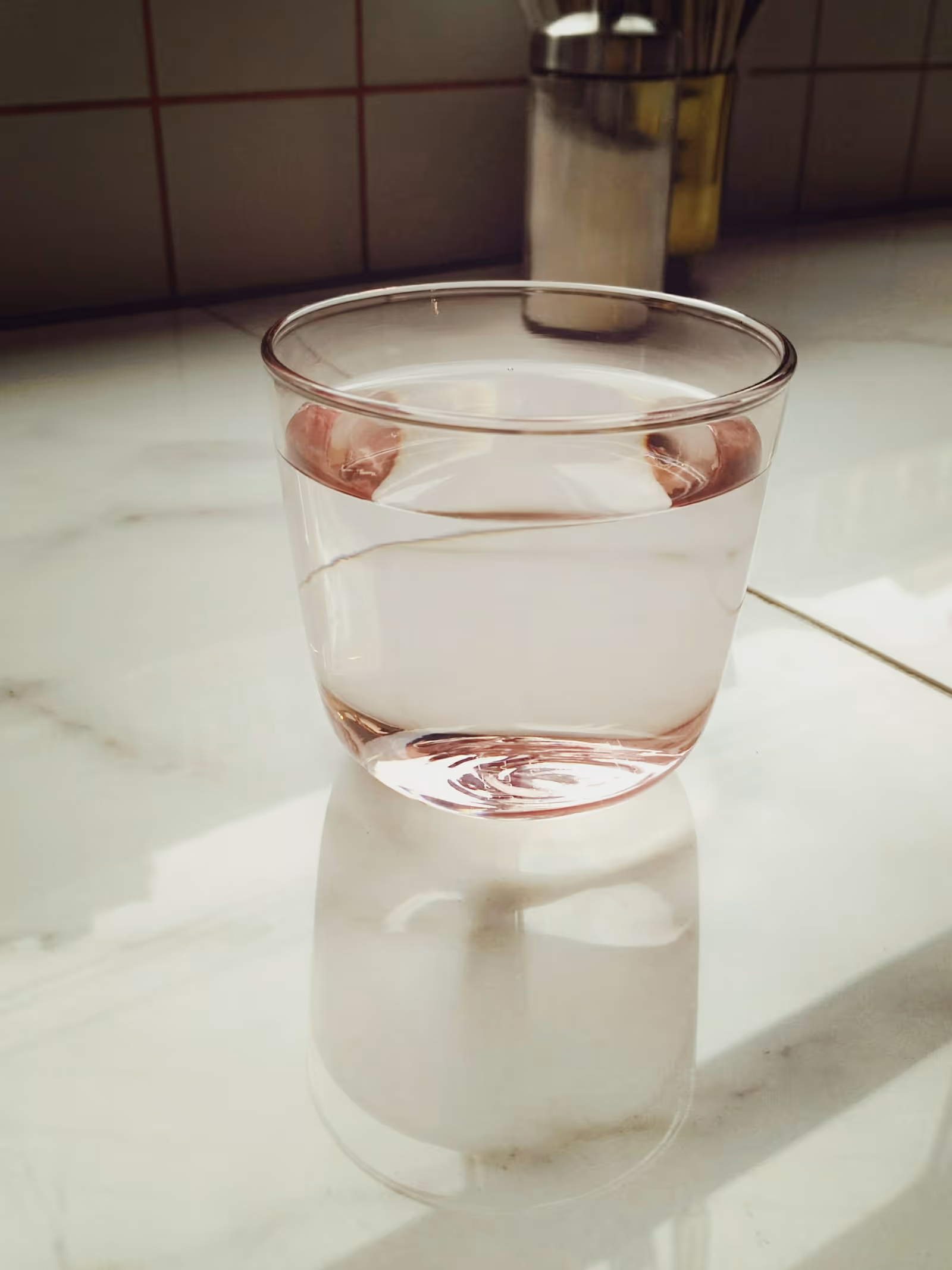 A plain glass of water on a kitchen counter; arsenic in well water has no color, taste, or smell, so clean-looking water can still contain it